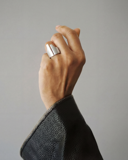 Hand wearing a silver ring on a plain background
